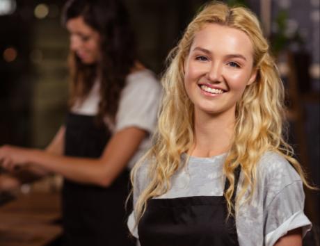 A woman smiling to the camera in their work uniform showcasing the work experience focus of this article "Work experience on CV"